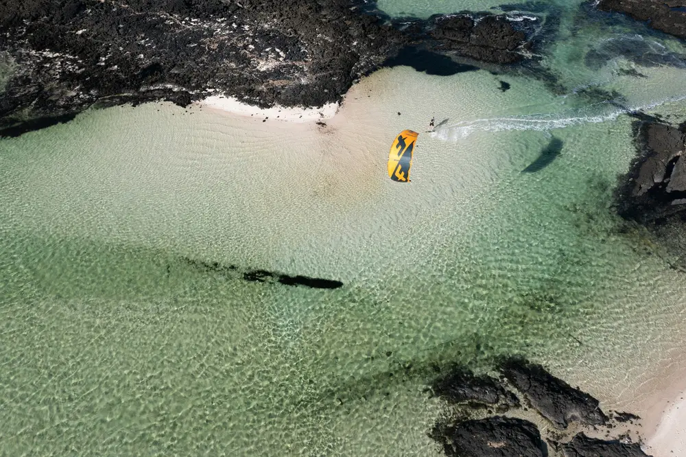 Vue aérienne d'un kitesurfeur dans un lagon d'eau peu profonde, conditions idéales pour apprendre le kitesurf
