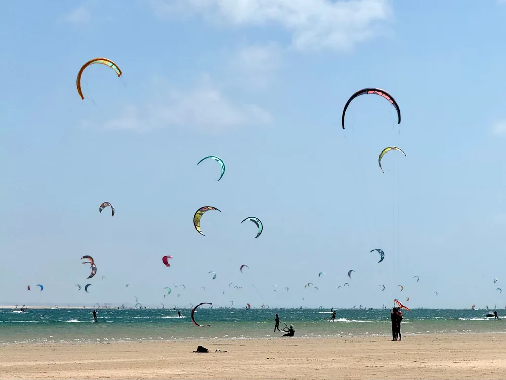 Dizaines d'ailes de kitesurf dans le ciel au dessus de la plage et de la lagune de Dakhla