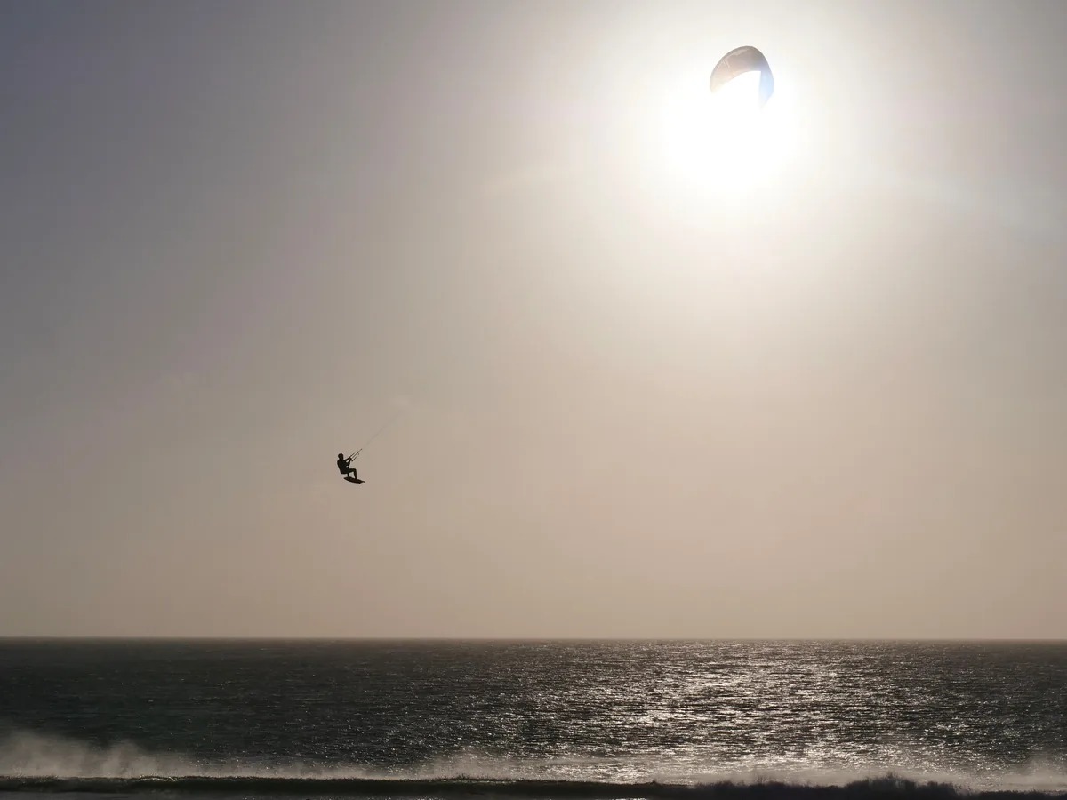 Kitesurfeur en plein saut à contre-jour au-dessus des vagues à Tarifa